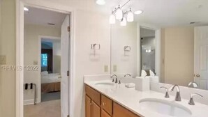 Une salle de bain moderne avec un double vasque, des meubles en bois et un grand miroir.