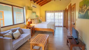 A spacious room with a bed, a sofa, a wooden table, and a television.