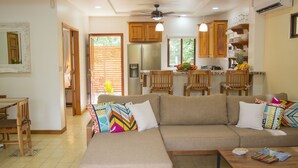 A living room with a sofa, a coffee table, and a dining area with chairs and a table.