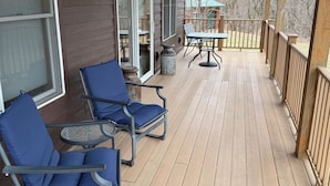 A covered outdoor deck with two blue chairs, a table, and a potted plant. - Quiet, secluded bluff top cabin with beautiful sunsets (Alma)