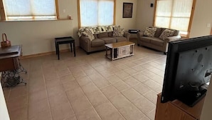 A spacious living room with two sofas, a coffee table, and a television on a wooden stand. - Quiet, secluded bluff top cabin with beautiful sunsets (Alma)