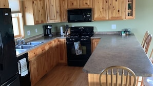 A kitchen with wooden cabinets, a black stove, a microwave, and a sink. - Quiet, secluded bluff top cabin with beautiful sunsets (Alma)