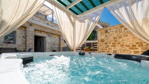 Een hottubgedeelte met stenen muren en een overdekte pergola.