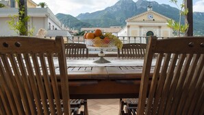 A wooden table with a fruit bowl in the center, surrounded by chairs, overlooking a mountainous landscape with a building in the background. - B&B L'Incanto,
The b&b in the historic center.. Just 2 km from the Amalfi Coast! (cava de' tirreni)