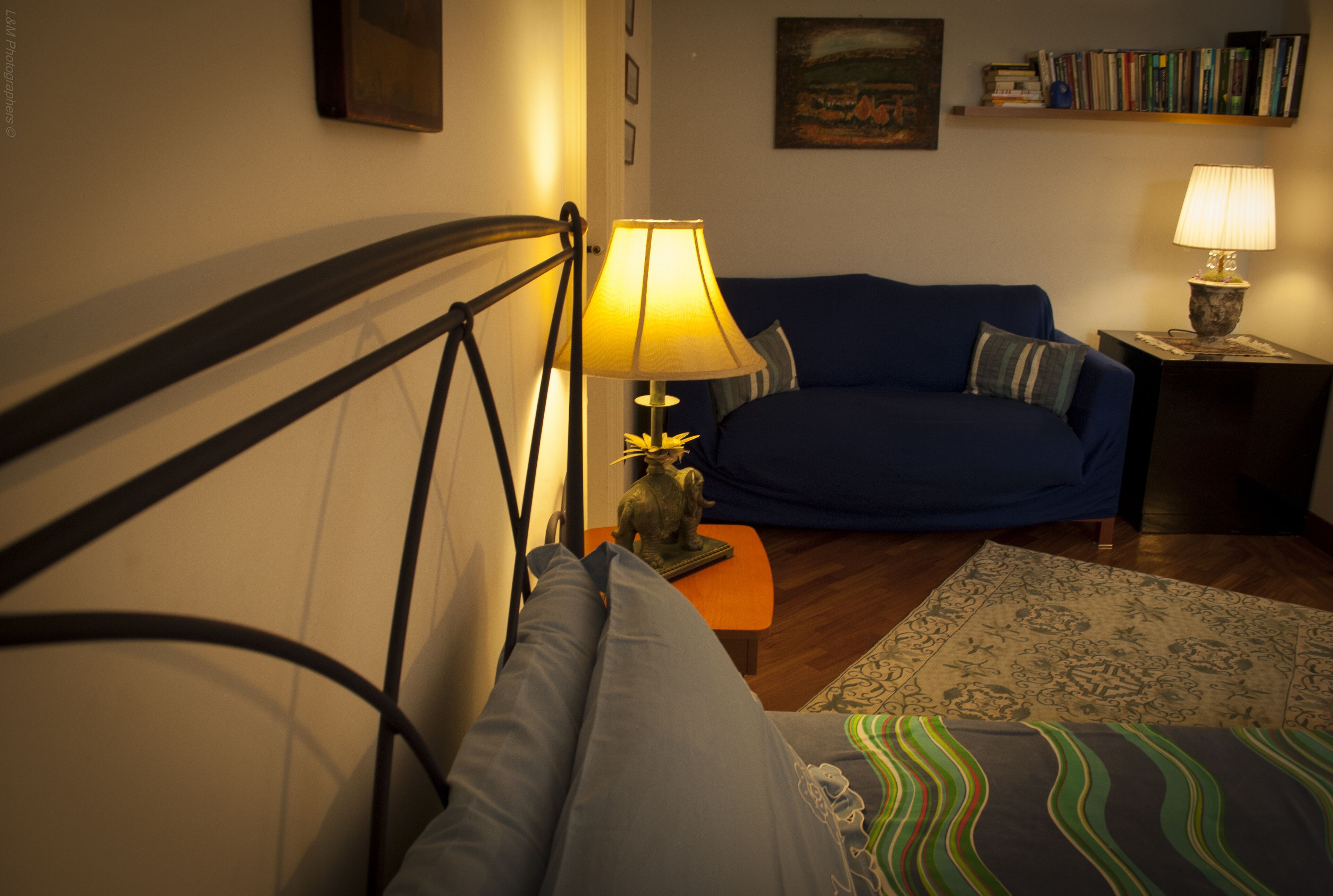 Un salon chaleureux avec un canapé bleu, une petite table sur laquelle est posée une lampe, et un tapis à motifs.