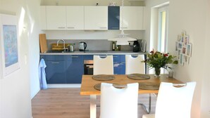 Una cocina moderna con armarios blancos, una mesa de comedor de madera y sillas blancas.