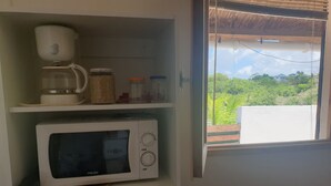 Eine Küche mit einer weißen Mikrowelle, einer Kaffeemaschine und Gläsern in den Regalen.