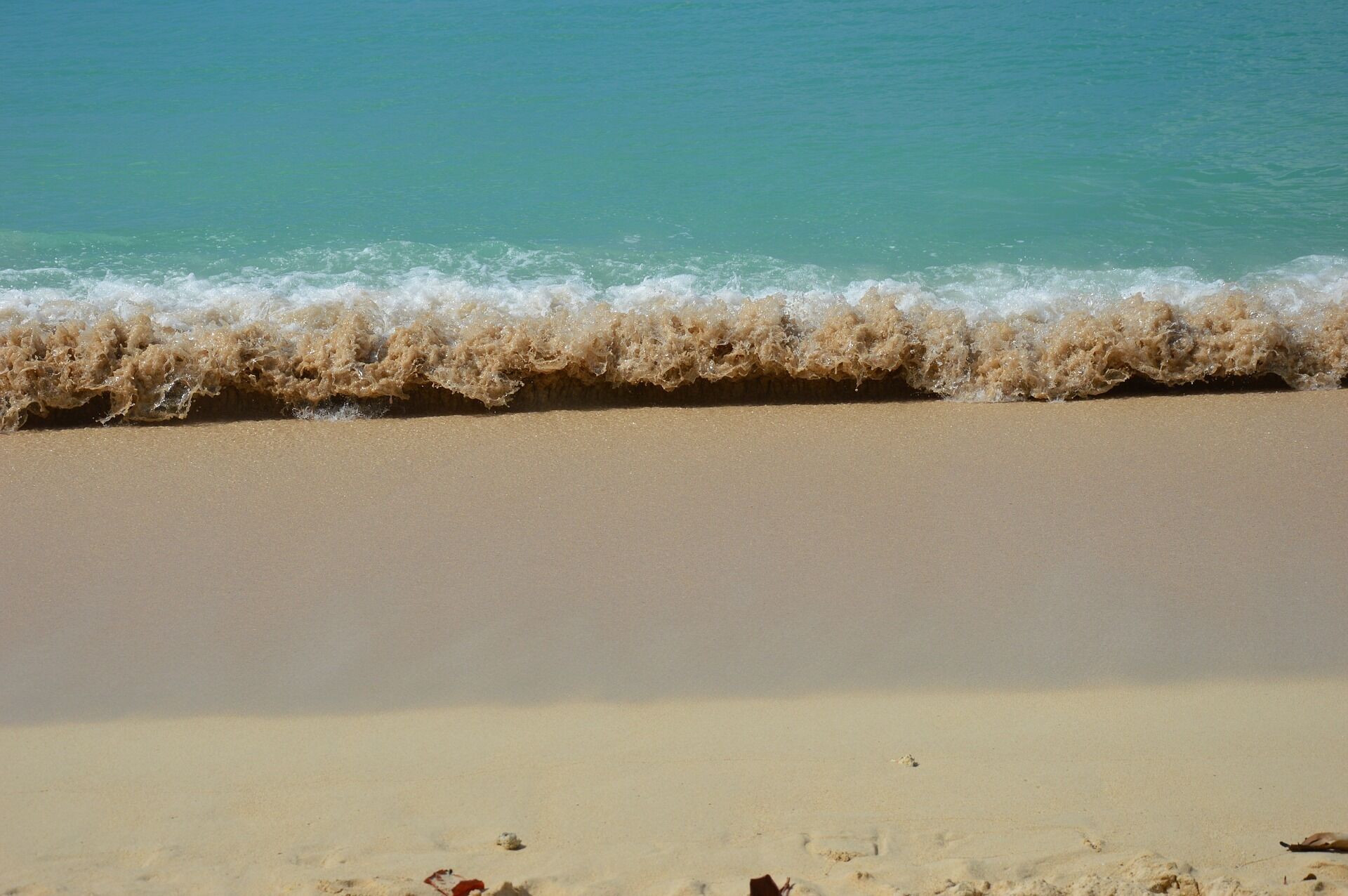 A beach with clear turquoise water and a sandy shore.