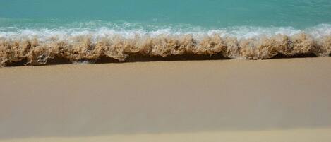 A beach with clear turquoise water and a sandy shore.