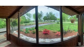 A covered porch with large windows overlooking a landscaped garden with red flowers and a swing set. - Mule Town Cottage, Historic Columbia TN. 3BR/2BA (Columbia)