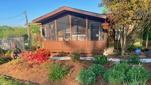 A wooden house with a covered porch, surrounded by a garden with various plants and flowers. - Mule Town Cottage, Historic Columbia TN. 3BR/2BA (Columbia)