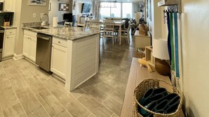A spacious kitchen with wooden ceiling, a central island, and a dining area in the background. - "The Turtle Nest" a 3bed/2 bath Condo in St Regis (New Listing) (North Topsail Beach)