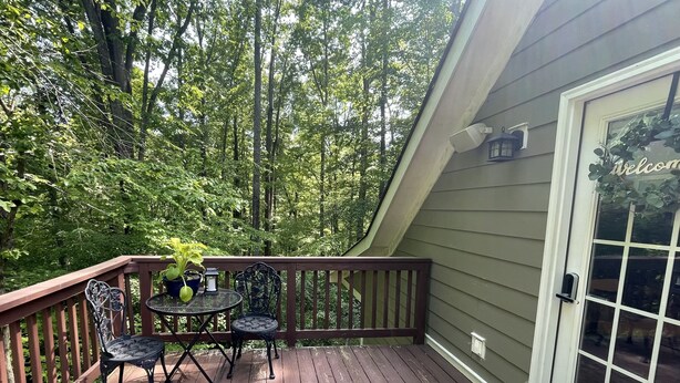 A wooden deck with a table and chairs, surrounded by lush greenery. - Wandering Bear’s Den Private Studio Near Crozet and Charlottesville (Charlottesville)