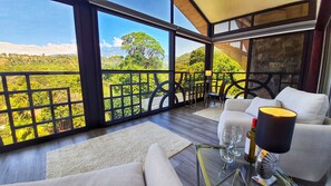 A modern room with large windows, a sofa, a glass table, and a view of a green landscape. - La Residencia by Villa Alejandro (Jaramillo)