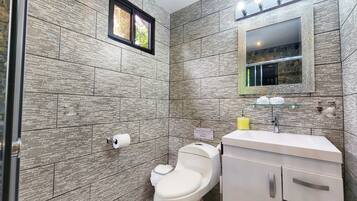 A modern bathroom with a tiled wall, a toilet, a sink, and a mirror.