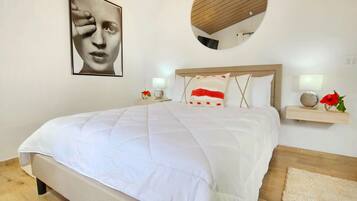 Un dormitorio con una cama grande, un espejo redondo, mesitas de noche con lámparas y un cuadro en la pared.