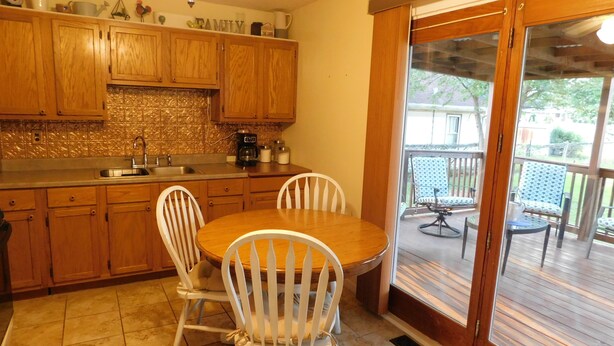 Une cuisine avec des meubles de rangement en bois, un évier et une table à manger avec des chaises.