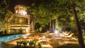 Un espace aménagé au bord de la piscine, avec des chaises longues et un bâtiment doté d’une tour.