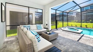 Ein moderner Außenbereich mit Pool, Korbmöbeln und großen Fenstern.
