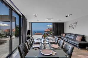 A modern dining area with a glass table, leather chairs, and a view of the sea. - Villa Ninona with Heated Pool II (Makarska)