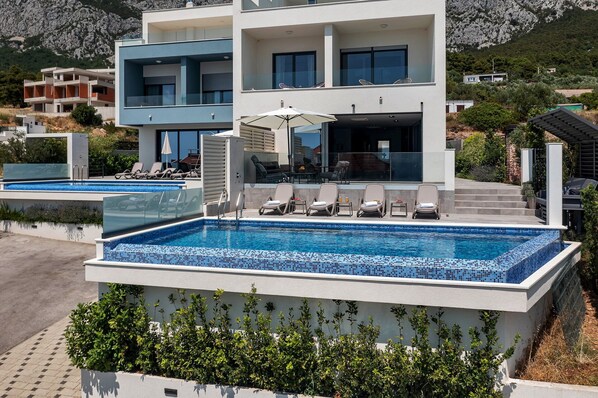 Un immeuble moderne à plusieurs étages, doté d’une piscine, d’un espace extérieur aménagé et offrant une vue sur le paysage environnant.