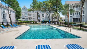 A swimming pool with blue and white lounge chairs, a pool ladder, and a fence. - Spacious 2 bd/2b Arcadian Dunes near Shore Drive, Ocean Annie's, golf & beach (Myrtle Beach)