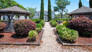 A garden pathway leading to two wooden gazebos, surrounded by various shrubs and trees. - Spacious 2 bd/2b Arcadian Dunes near Shore Drive, Ocean Annie's, golf & beach (Myrtle Beach)