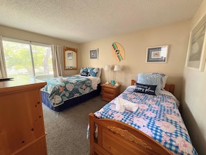 A bedroom with two beds, a dresser, a nightstand, and a window with curtains. - Spacious 2 bd/2b Arcadian Dunes near Shore Drive, Ocean Annie's, golf & beach (Myrtle Beach)