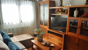 Sala de estar con sofá, televisor, aparador de madera y elementos decorativos.