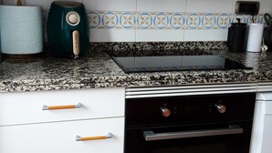 Una cocina con armarios blancos, un horno negro y un tostador color verde azulado.