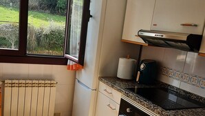 Una cocina con ventana, radiador, estufa y lavavajillas.