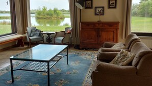 Un salón con vistas a un lago, un sofá, una mesa de centro y un aparador.
