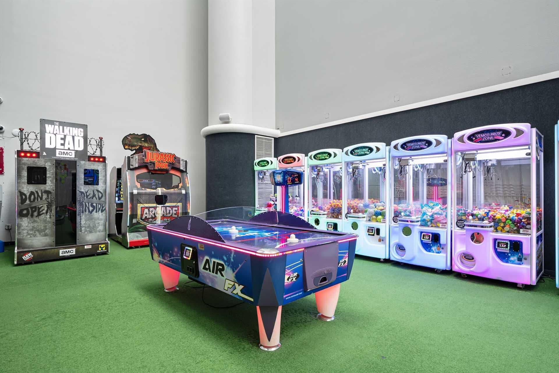 A gaming arcade with various machines including a pool table, claw machines, and arcade cabinets.