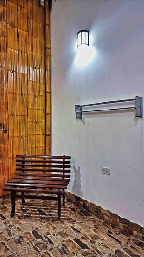 A bench in a room with a stone floor and a wall-mounted light fixture.