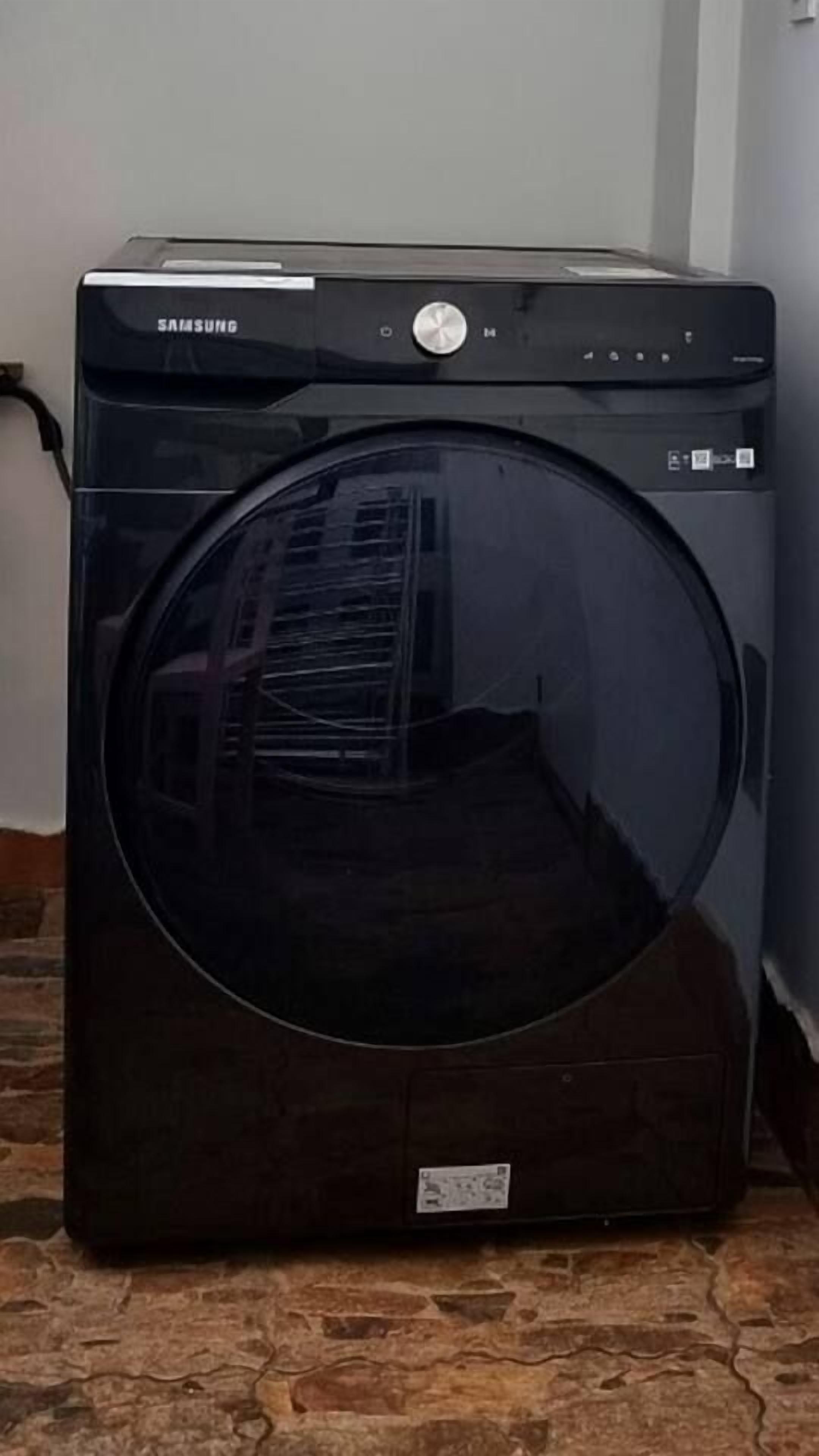 Máquina de lavar roupa Samsung preta com painel de controle e porta espelhada.