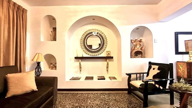 A living room with a sofa, a chair, a fireplace, and a mirror on the wall. - Luxury 2BR/2BA w/ Jacuzzi - Walk to Beach & Castle (Chancay)