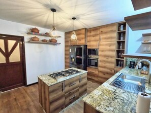 A modern kitchen with wooden cabinets, a stainless steel sink, and a built-in gas stove. - Luxury 2BR/2BA w/ Jacuzzi - Walk to Beach & Castle (Chancay)