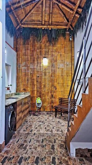 A room with a bamboo wall, a stone floor, a wooden bench, and a staircase. - Luxury 2BR/2BA w/ Jacuzzi - Walk to Beach & Castle (Chancay)