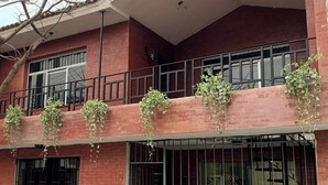 A multi-story building with a brick facade, multiple windows, and balconies adorned with hanging plants.