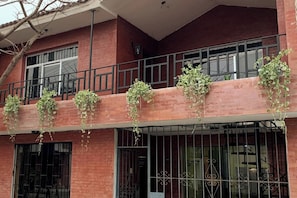 A multi-story building with a brick facade, multiple windows, and balconies adorned with hanging plants. - Luxury 2BR/2BA w/ Jacuzzi - Walk to Beach & Castle (Chancay)