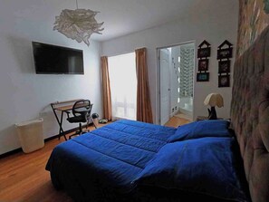 A bedroom with a bed, a desk, a chair, a television, and a window with curtains. - Luxury 2BR/2BA w/ Jacuzzi - Walk to Beach & Castle (Chancay)