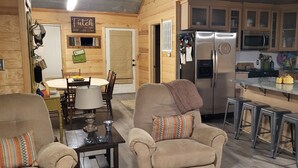 Una cocina acogedora con armarios de madera, un refrigerador de acero inoxidable y un comedor con mesa y sillas.