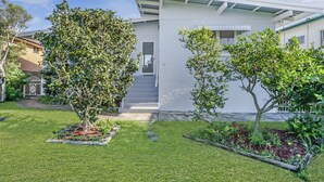 Una casa moderna con un césped cuidado y dos árboles en el jardín delantero.