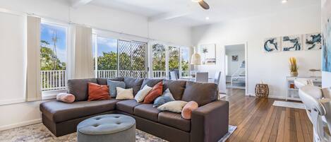 A spacious living room with a sectional sofa, ottoman, and large windows.