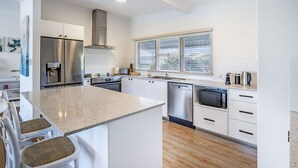 Una cocina moderna con armarios blancos, electrodomésticos de acero inoxidable y una isla grande con taburetes de bar.
