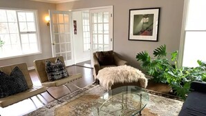 A living room with a glass coffee table, a sofa with patterned cushions, a fluffy rug, and a large plant. - Private Country Getaway (Bedford Hills)