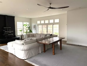 A spacious living room with a large sectional sofa, a wooden coffee table, and a ceiling fan.