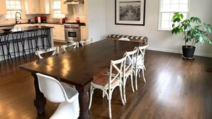 A spacious kitchen with a large dining table, white chairs, and a chandelier. - Private Country Getaway (Bedford Hills)