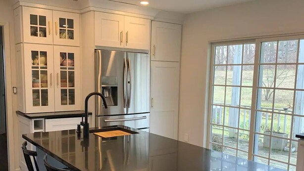 A modern kitchen with a large island, white cabinetry, stainless steel appliances, and a view through large windows. - Private Country Getaway (Bedford Hills)