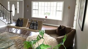 A spacious living room with a large window, a staircase, and a ceiling fan. - Private Country Getaway (Bedford Hills)